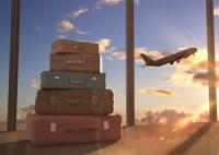 Urlauber auf den Kapverden können künftig bereits im Hotel ihr Gepäck für den Rückflug aufgeben. Ein Stapel Koffer im Vordergrund ein startendes Flugzeug im Hintergrund