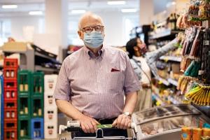 Älterer Mann mit Maske und Einkaufswagen in einem Berliner Supermarkt.