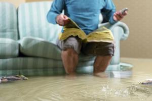 Mann auf Couch bei Hochwasser