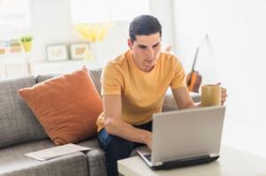 Reisende können den XL-Sitz auch online hinzu buchen. Junger Mann sitzt vor Laptop
