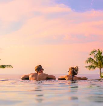 Paar im Pool bei Sonnenuntergang