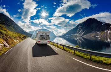 Wohnmobil mit Fahrrädern fährt entlang eines Bergsees.