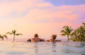 Paar im Pool bei Sonnenuntergang