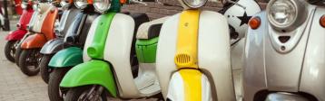 Ein Reihe verschiedener bunter Roller steht vor einem Haus.