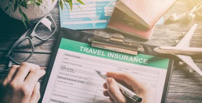 Person füllt Formular für Reiseversicherung aus.