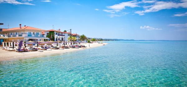 Meer und Strand von Pefkochori auf Chalkidiki mit Häusern im Hintergrund.