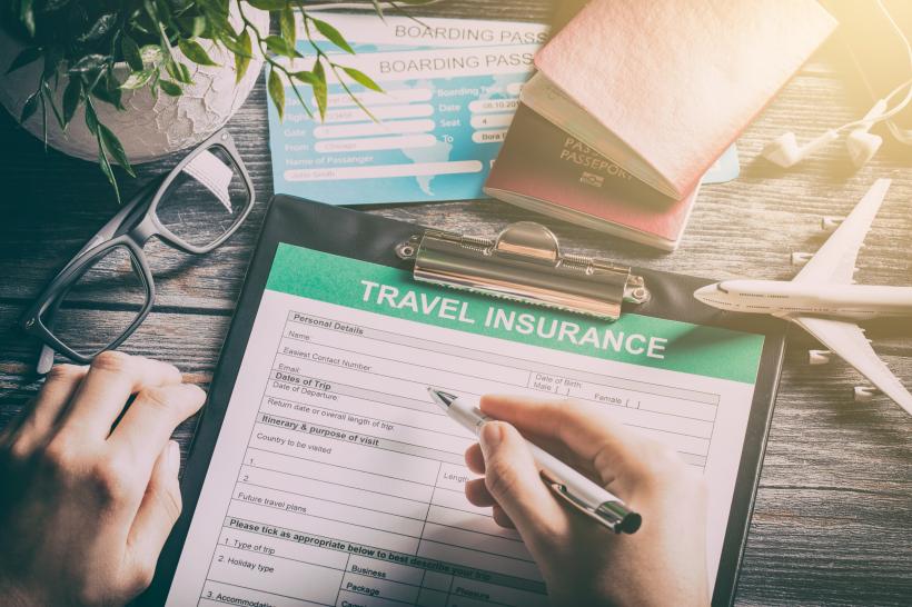 Person füllt Formular für Reiseversicherung aus.