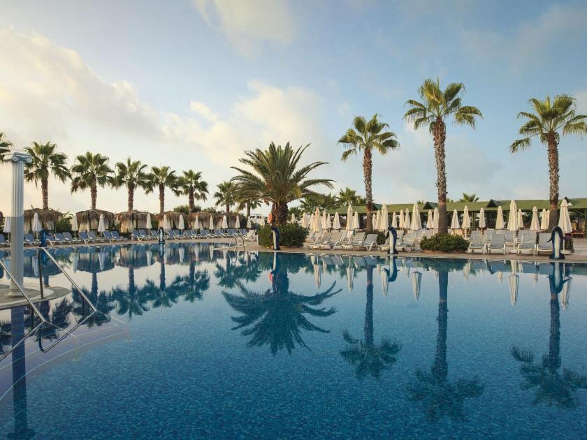 Luxuriöser Hotelpool mit Palmen und Sonnenliegen im Botanik Platinum Hotel, perfekter Urlaubsort in der Türkei.